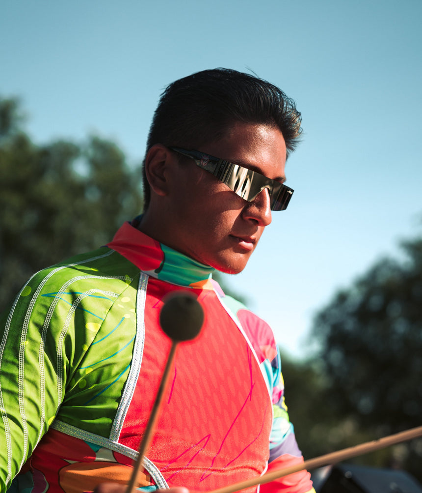 Person wearing a colorful jacket and sunglasses outdoors with trees in the background